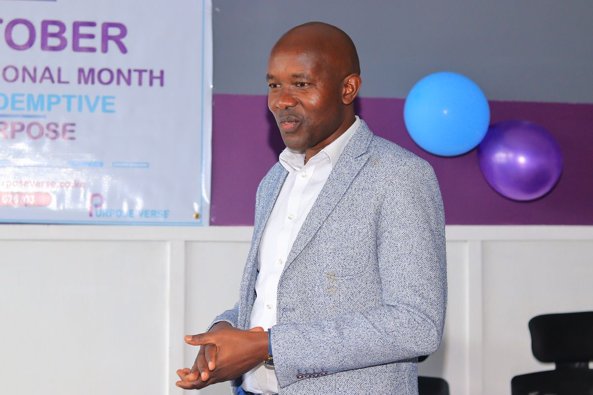 A speaker beside the October, International Month of Redemptive Purpose banner